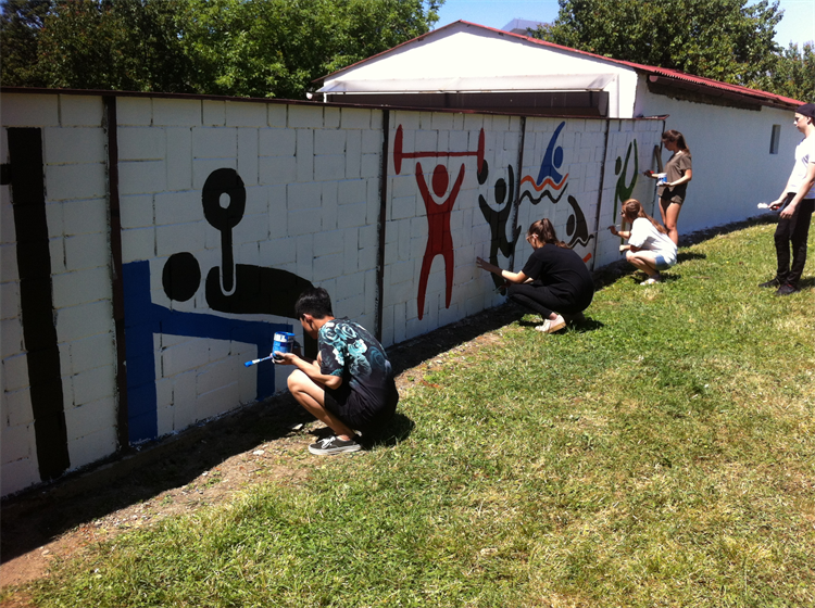 Studenti gymnázia vyzdobili stěnu malbou cvičících postav. 